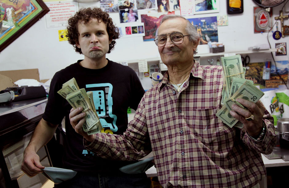 Kyle MacDoland of The Red Paper Clip Project and one of the team members with The Store Buyout Project with shop owner Hercules Dimitratos.