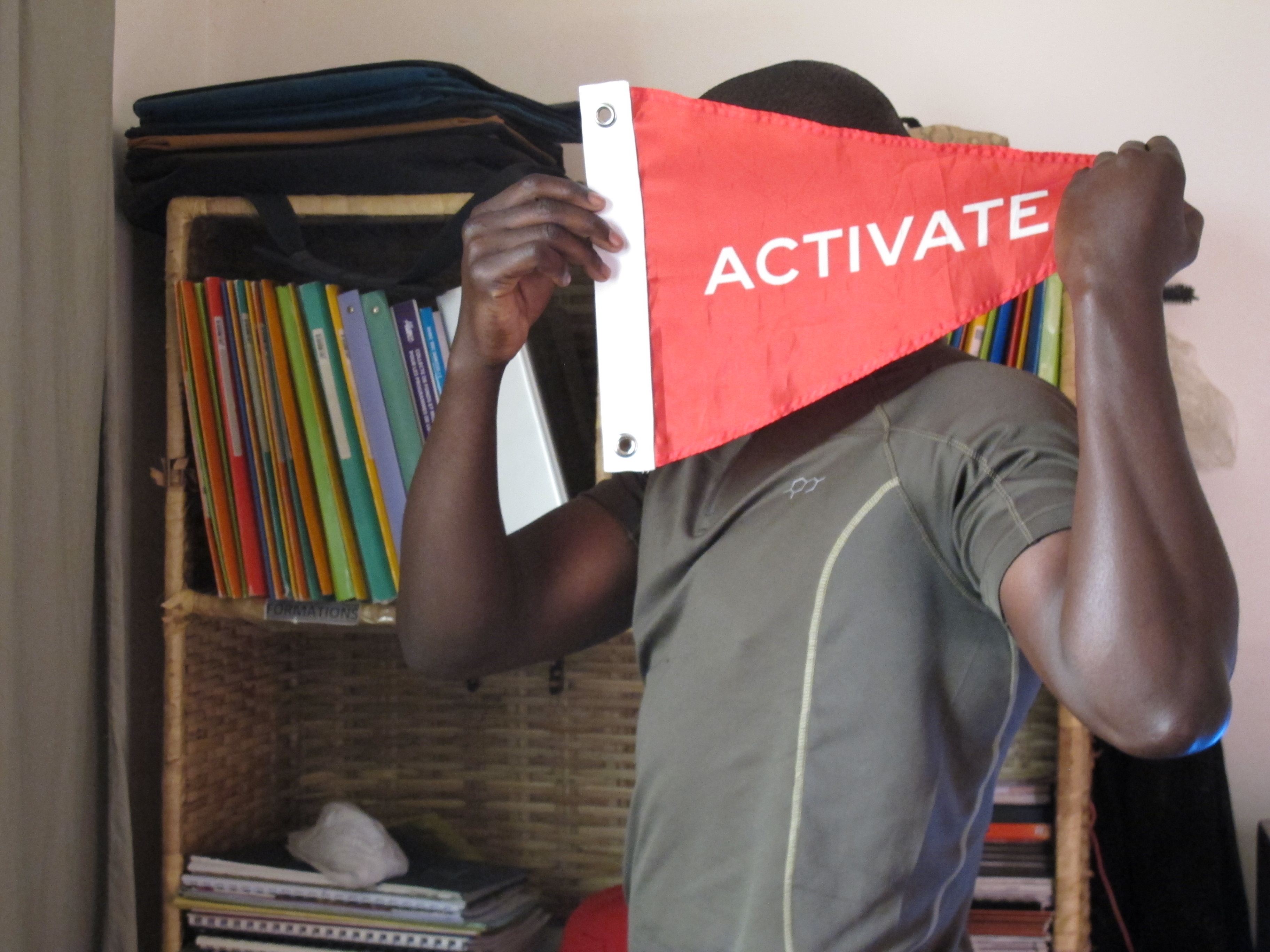 Souleymane in his apartment in Dakar, Senegal with our Activate flag. He is covering his face to protect his identity.